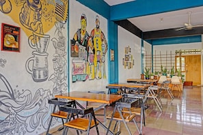 A café with tables, chairs, and a mural on the wall.