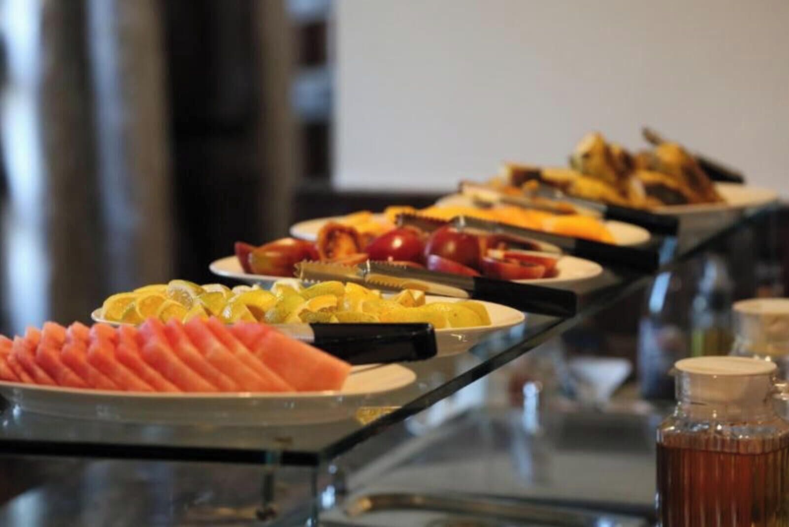 A buffet with various food items including sliced fruits, vegetables, and meats.
