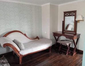 A room with a wooden sofa, a vanity with a mirror, and a patterned wallpaper. - The Treetops Lodge (Aberdare National Park)