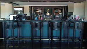 Un espace bar comprenant un comptoir, des tabourets de bar et une variété de bouteilles.