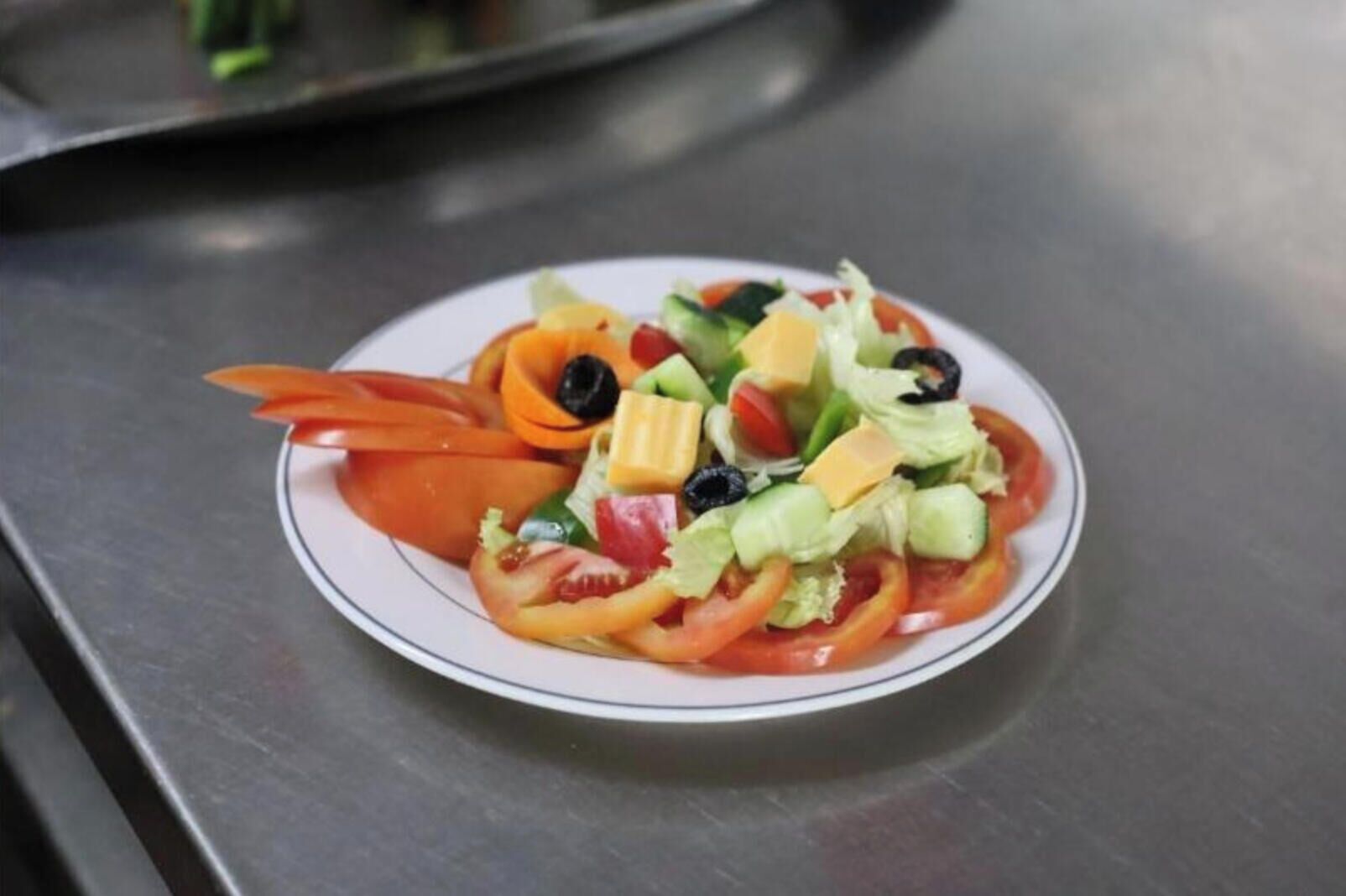 Ensalada con diversas verduras y queso, sobre un plato blanco.