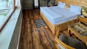 A wooden-paneled room with a bed, a table, and a view through a window.