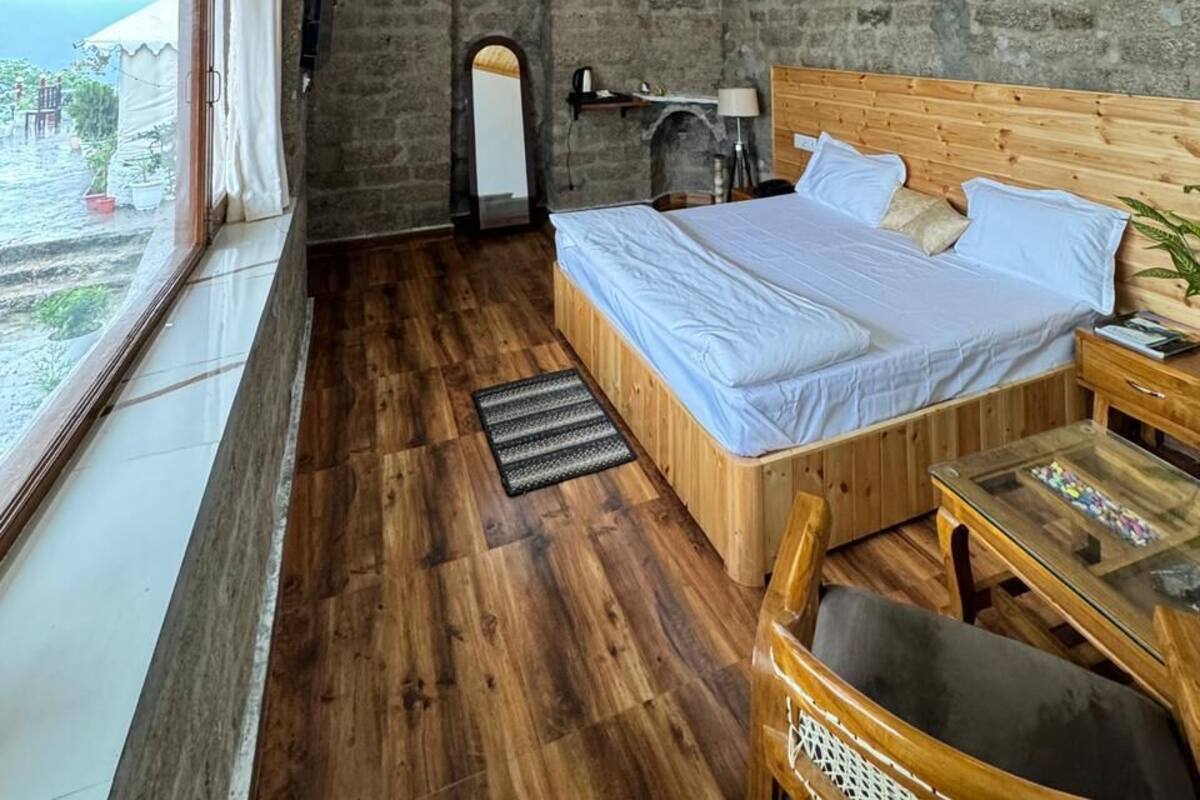 Una habitación con paneles de madera, una cama, una mesa y vistas a través de una ventana.