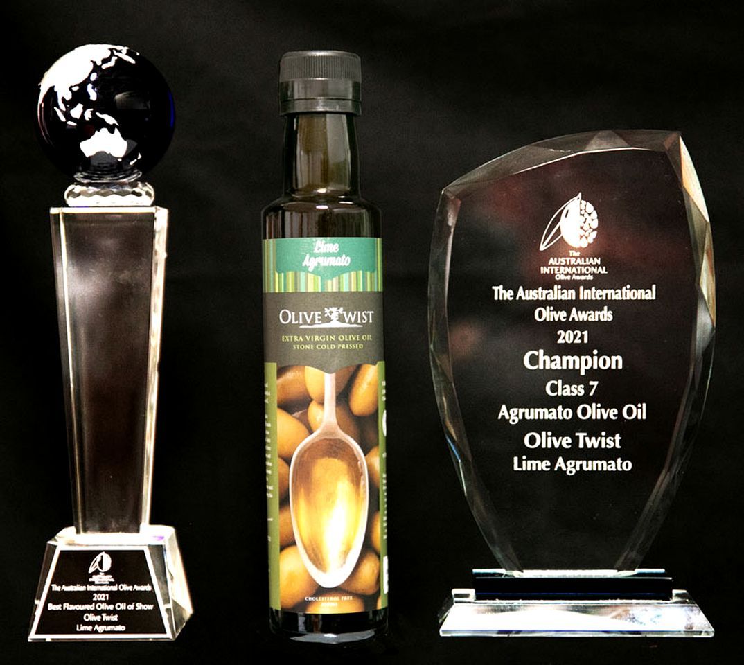 Three awards: a globe trophy, a bottle of olive oil, and a crystal award plaque.