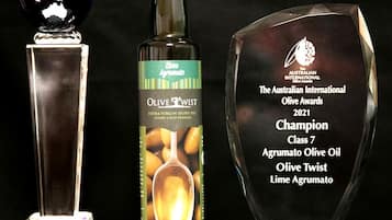Three awards: a globe trophy, a bottle of olive oil, and a crystal award plaque.