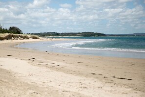 Une plage avec un rivage sablonneux, des vagues douces et un ciel dégagé.