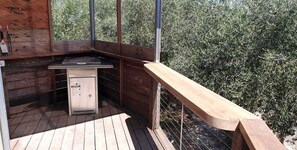 A wooden deck with a built-in grill and a small refrigerator.