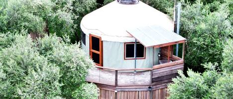 Une tour-maison en bois dotée d’un balcon, entourée d’une végétation luxuriante.