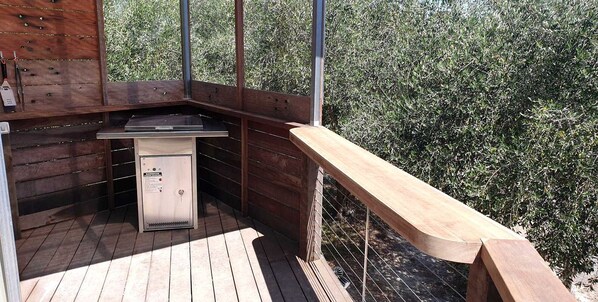 A wooden deck with a built-in grill and a small refrigerator.