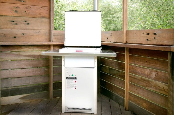 Una parrilla portátil de barbacoa con un gabinete blanco en la parte inferior, frente a un fondo de valla de madera.