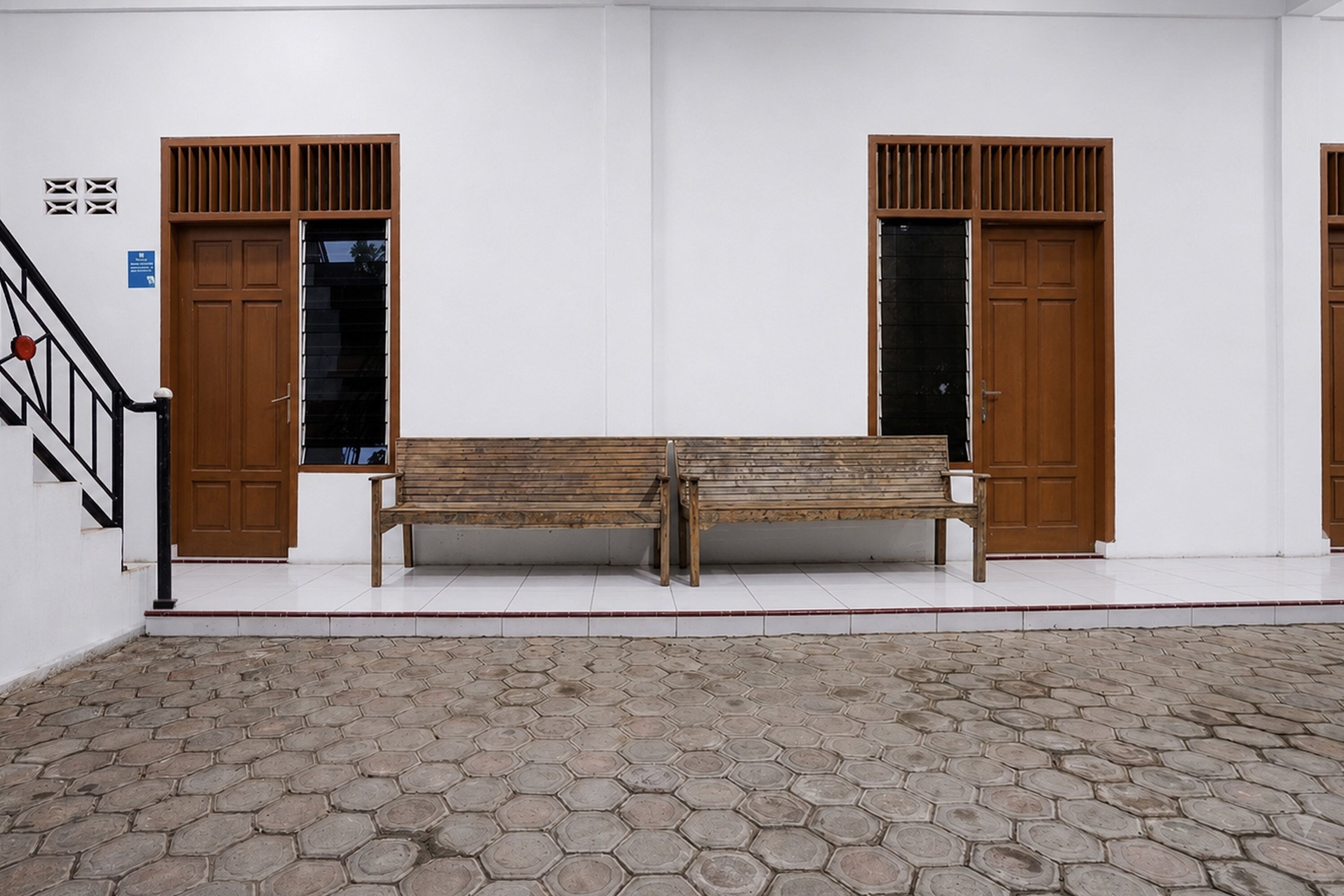 A room with two wooden doors, a bench, and a tiled floor.