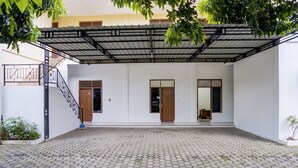 A courtyard with a tiled floor, a covered area with a metal roof, and two wooden doors. - Hotel O near RS Harapan Bunda formerly Q (Banda Aceh)