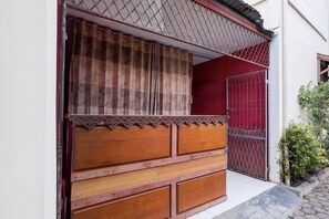 Un banco de madera tradicional con una cortina estampada que cubre parcialmente una ventana.