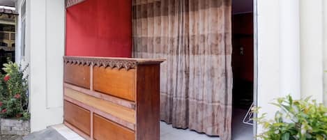 A wooden cabinet with drawers and a red panel, a patterned curtain, and a tiled floor.