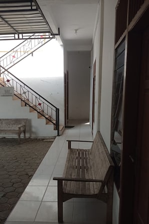 A corridor with a wooden bench, a staircase, and a door. - Hotel O near RS Harapan Bunda formerly Q (Banda Aceh)