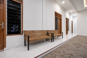 A hallway with a wooden bench, white walls, and a tiled floor. - Hotel O near RS Harapan Bunda formerly Q (Banda Aceh)