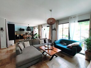 Ein modernes Wohnzimmer mit einem Ecksofa, einem blauen Sessel und einem Holztisch.