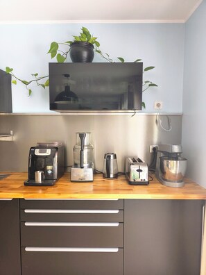 Eine Küche mit Kaffeemaschine, Mixer, Toaster und einem Fernseher, der über der Arbeitsfläche angebracht ist.