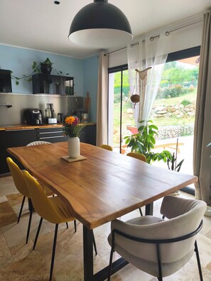Eine moderne Küche mit einem Holztisch, gelben Stühlen und Blick auf einen Garten durch eine Glastür.