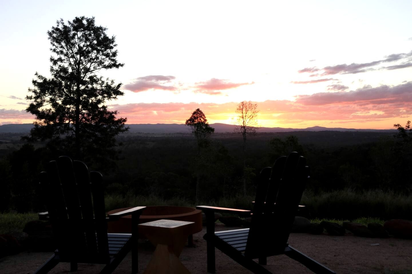 A sunset view with chairs and a table in a natural setting.