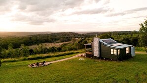 A modern house with a large glass window, a stone chimney, and a solar panel on the roof, surrounded by a lush green landscape. - Stunning Cabin with a Private Hot Tub and Views of Bunya Mountain, Perfect for a Queensland Getaway (Neumgna)