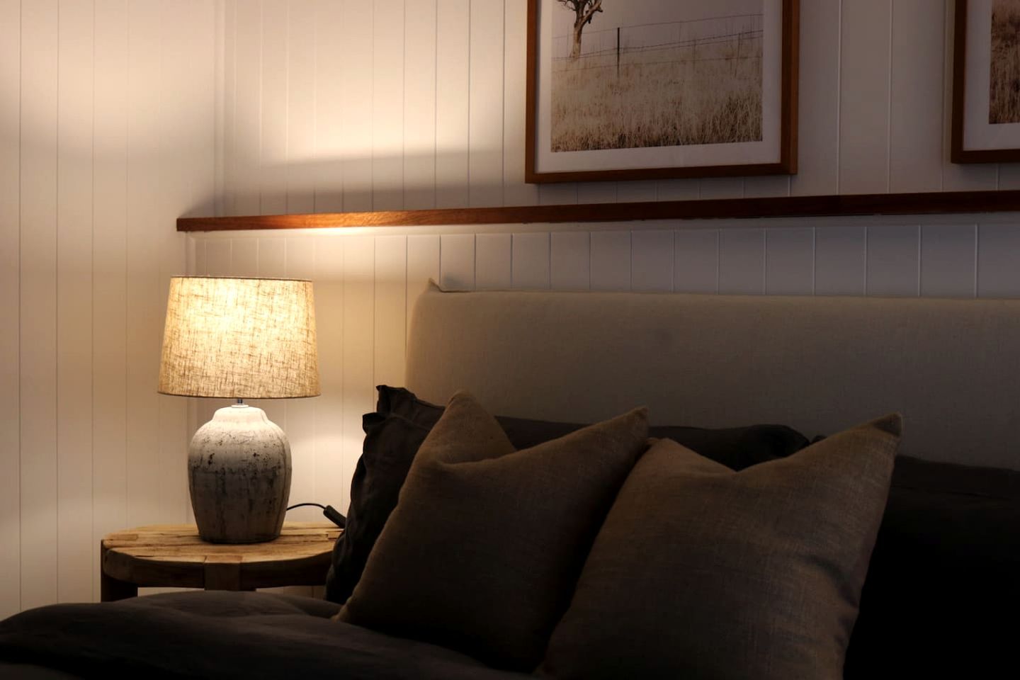 A bedroom with a bed, a nightstand with a lamp, and a framed picture on the wall.