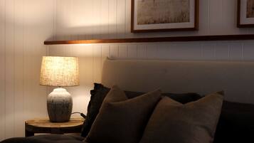 A bedroom with a bed, a nightstand with a lamp, and a framed picture on the wall.
