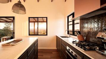 A modern kitchen with a large window, wooden flooring, and a view of the outdoors.
