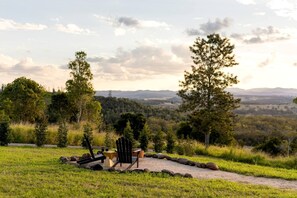 Un espacio al aire libre con vistas panorámicas, con una mesa y sillas, rodeado de un paisaje natural y árboles.