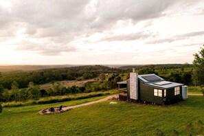 A modern house with a large glass window, a stone chimney, and a solar panel on the roof, surrounded by a lush green landscape. - Stunning Cabin with a Private Hot Tub and Views of Bunya Mountain, Perfect for a Queensland Getaway (Neumgna)