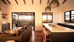 Een moderne keuken met een groot schiereiland, een zithoek met een bank en een balkon met uitzicht.