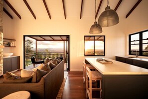 Uma cozinha moderna com uma ilha grande, uma área de refeições com sofá e uma varanda com vista.