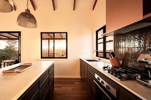 A modern kitchen with a large window, wooden flooring, and a view of the outdoors.