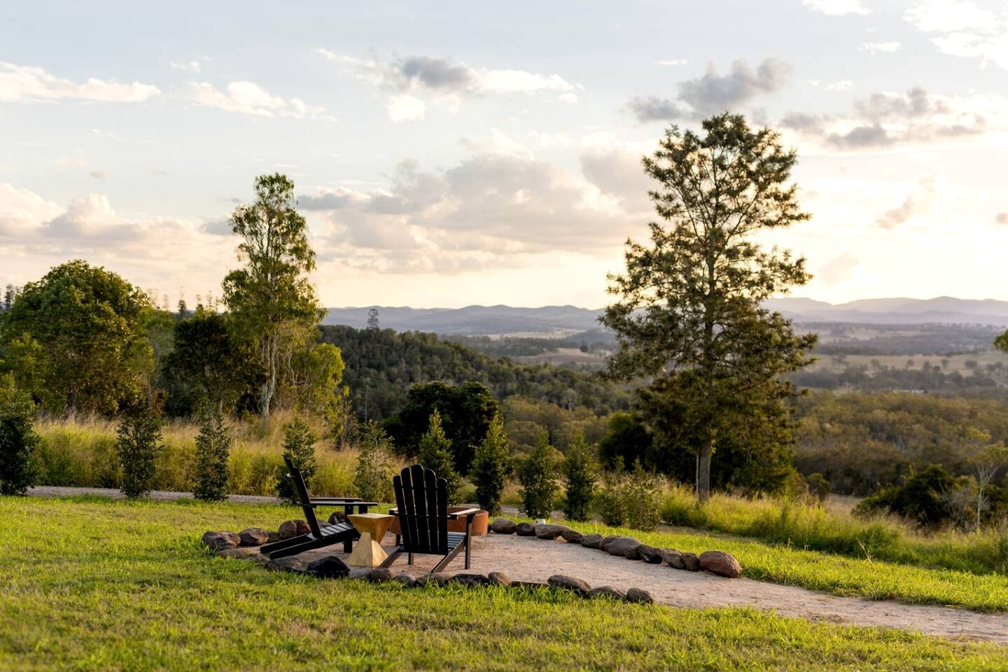 A scenic outdoor seating area with a table and chairs, surrounded by a natural landscape and trees.