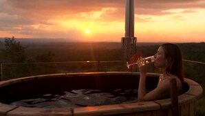 A person in a hot tub with a sunset in the background. - Stunning Cabin with a Private Hot Tub and Views of Bunya Mountain, Perfect for a Queensland Getaway (Neumgna)