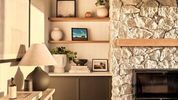 A cozy living room with a stone fireplace, wooden shelves, and a flat-screen TV.