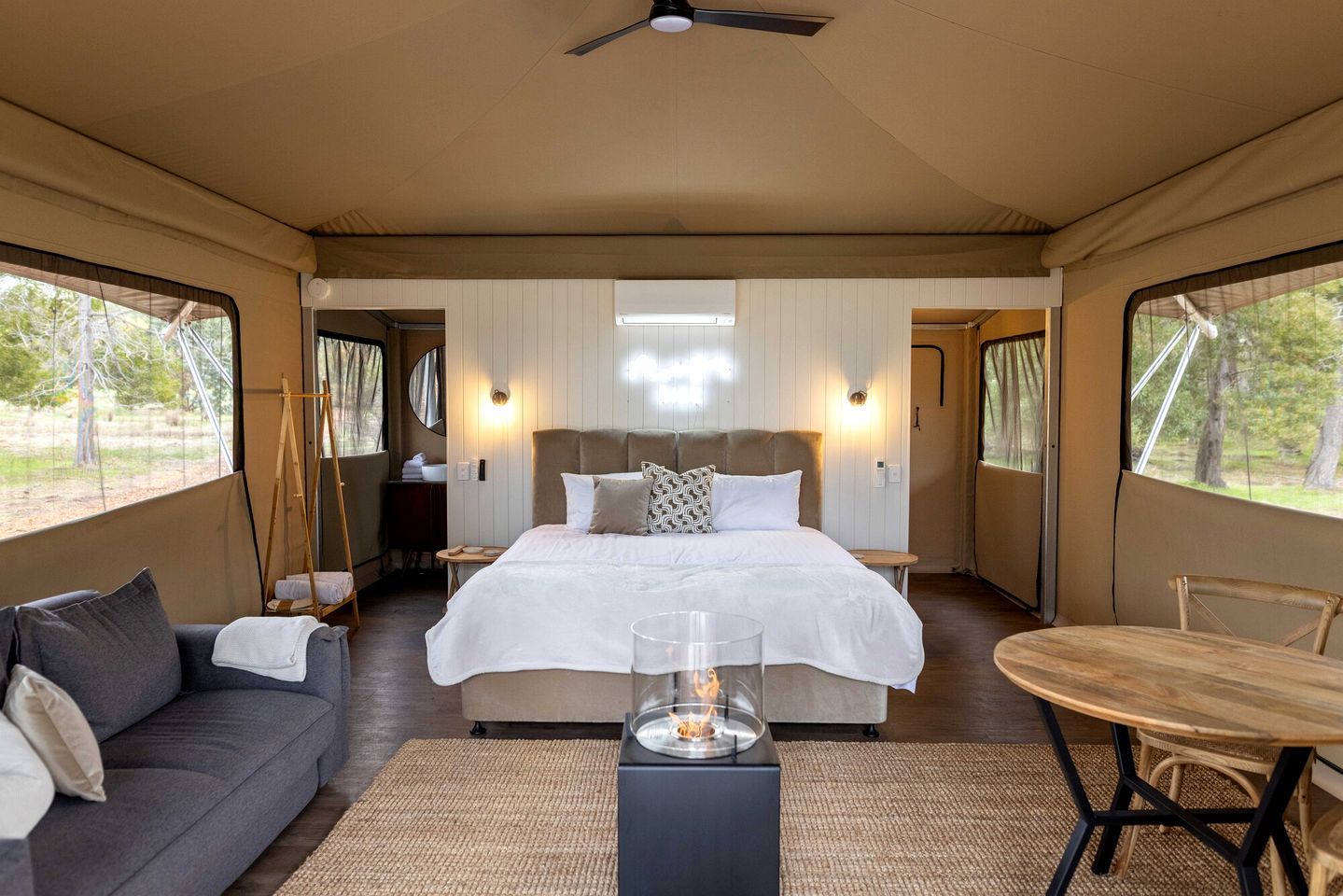A bedroom with a bed, a sofa, a table, and a ceiling fan.