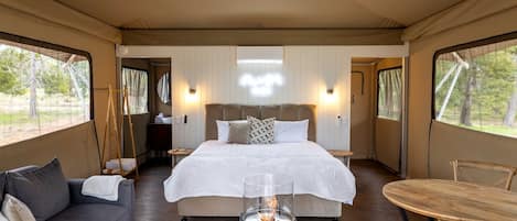 A bedroom with a bed, a sofa, a table, and a ceiling fan.