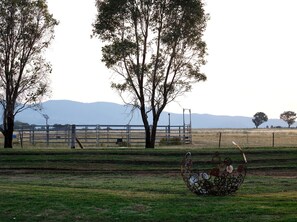 Un campo cercado con árboles y una escultura de metal.