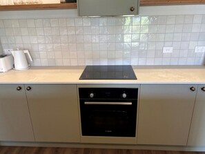 Eine Küche mit Bosch-Ofen, weiß gefliestem Fliesenspiegel und einer helben Arbeitsplatte.