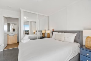 Ein Hotelzimmer mit einem großen Bett, einem Badezimmer mit Waschbecken und Blick ins Freie.