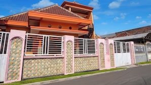 A residential building with a tiled roof, a gated entrance, and a paved driveway.