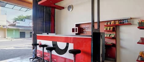 A bar area with stools, a counter, and shelves with bottled beverages.
