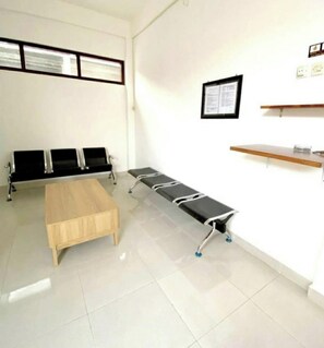 A clinical room with a wooden bench, a reception desk, and a wall-mounted display. - OYO 95290 Incess Diana Syariah (Probolinggo)