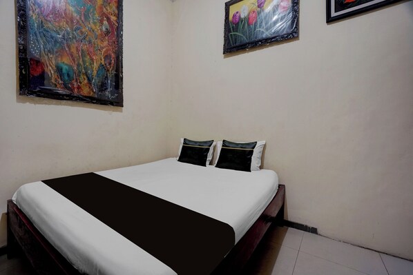 A bedroom with a bed, two pillows, and two wall-mounted paintings. - OYO 95290 Incess Diana Syariah (Probolinggo)