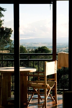 A wooden chair and table on a balcony with a view of a landscape.