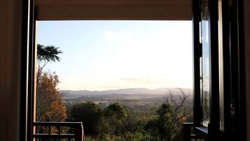 A view from a window with a view of a landscape, including trees and distant hills.