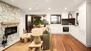 A modern kitchen with white cabinets, a stone wall, and a fireplace.