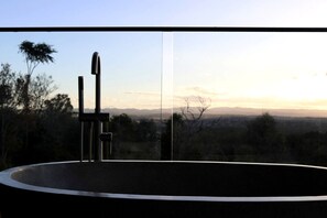 Ein runder Pool mit einem modernen Wasserhahn, umgeben von einem Balkon mit Blick auf eine entfernte Landschaft.