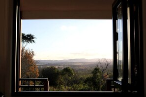 A view from a window with a view of a landscape, including trees and distant hills.